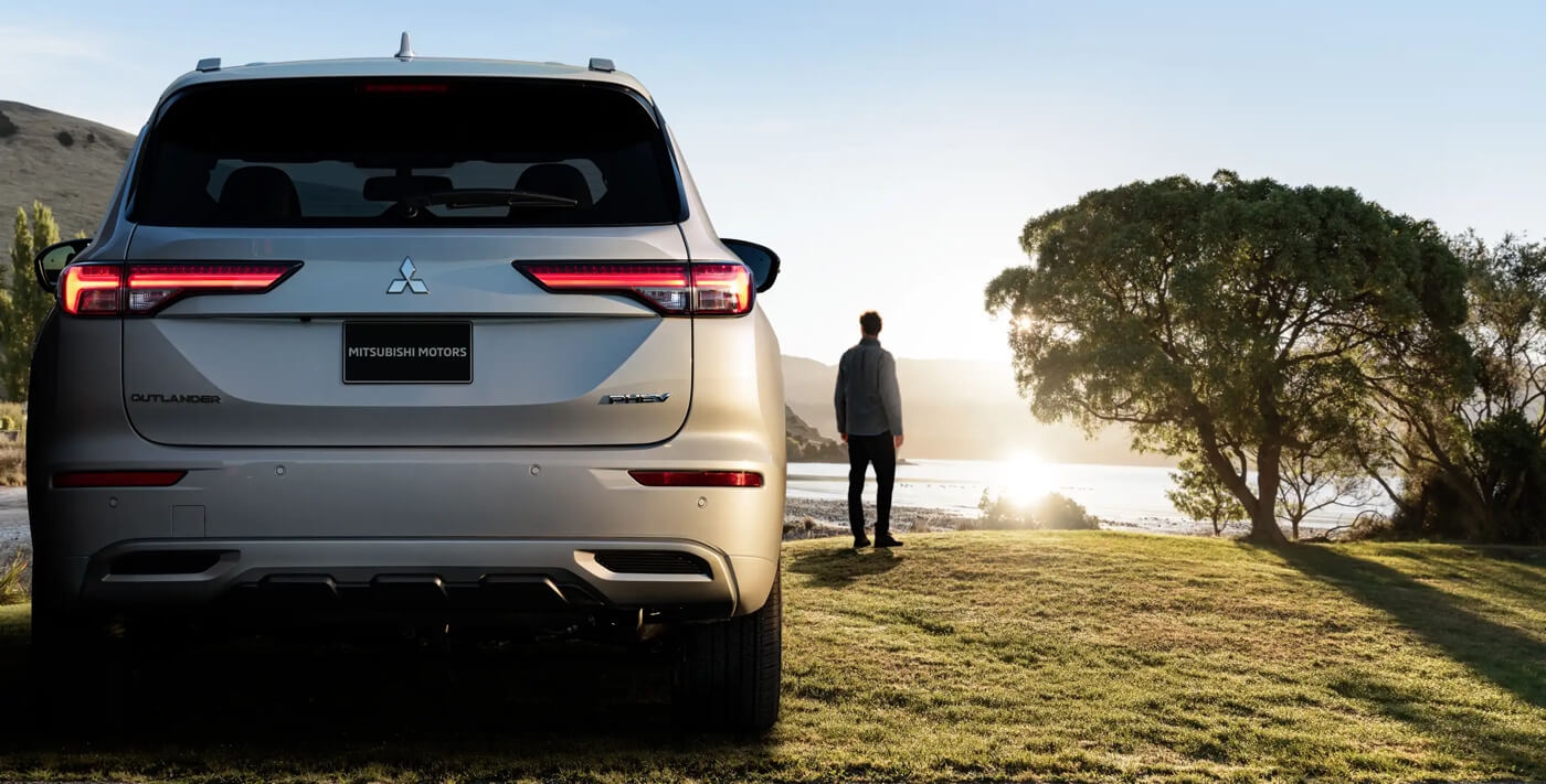 Vue arrière du Mitsubishi Outlander PHEV 2024 au levé du soleil.